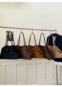 Vijf minimalistische suède draagtassen in verschillende kleuren aan een metalen hanger