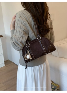 Detail of vintage brown suede shoulder bag with metallic eyelets and baseball charm