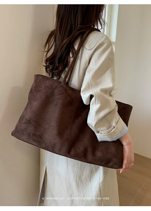 Detail van donkerbruine suède draagtas met grote capaciteit en een retro minimalistische look