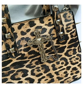 Détail du sac léopard avec breloque croix gothique et clous carrés vintage