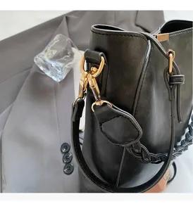 Close-up of black bucket bag featuring glossy leather texture and golden metal hardware
