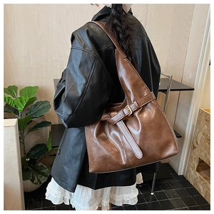Detailed view of brown oil-wax leather tote bag with vintage buckle on a model shoulder