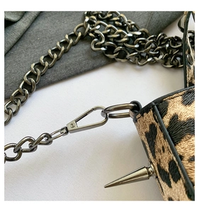 Détail du sac à main léopard avec des clous argentés et une bandoulière en chaîne métal