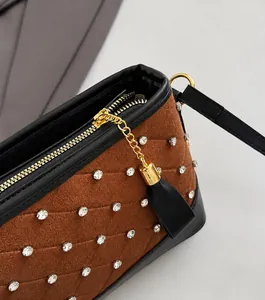 Détail de la fermeture dorée et des strass sur un sac seau marron mat vintage