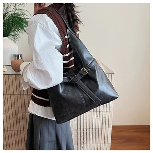 Detail of minimalist black tote bag with vintage metal buckle and matte leather texture