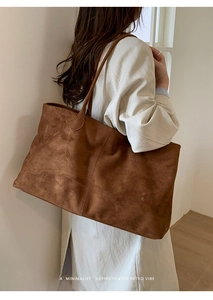 Detailopname van de grote karamelbruine suède shopper gedragen door een model