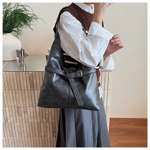 Close-up detail of black PU leather tote bag with buckle strap on a shoulder strap