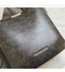 Close-up of pebble-grain leather bag detail with gold metal trim and logo