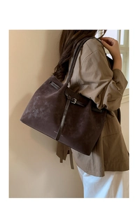 Detailed side view of a large brown suede tote bag featuring sleek leather straps