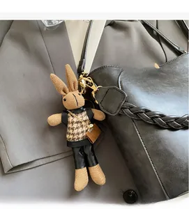 Detail of creative knitted rabbit charm with houndstooth vest on a black leather handbag