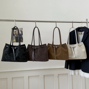 Collection of four large suede tote bags in black, coffee, tan and cream on a rack