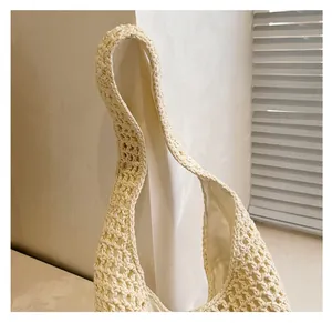 Detail of wide woven strap and cream hollow crochet texture on casual beach bag