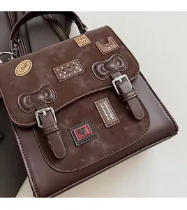Detail of dark brown faux leather bag with cat patches, heart embroidery, and dual buckles