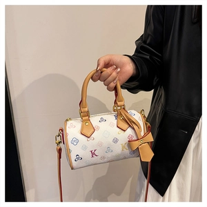 Detail of white Boston bag with floral patterns, leather handles and bow charm