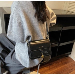 Gros plan d'un sac bandoulière en similicuir noir avec détails dorés et lettrage chic