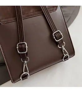 Detail of dark brown leather handbag featuring silver metal hooks and neat stitching