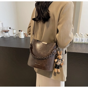 Detail of vintage brown leather bucket bag with woven handle and cute rabbit charm