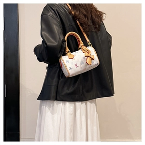 Detail of white Boston bag with colorful floral prints and a stylish leather bow charm