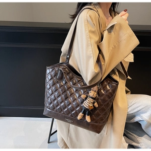 Detail of dark brown quilted tote bag with rabbit charm and Fashion Bag print