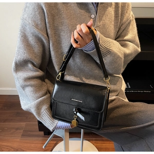 Détail du sac à bandoulière en cuir noir avec garniture dorée et logo Fashion & Bag