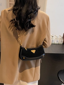 Sac bandoulière chic en noir mat avec chaîne dorée porté par un mannequin en studio