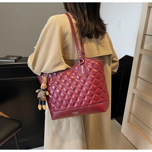 Detail of burgundy quilted tote bag with cute bunny charm and fashion bag lettering