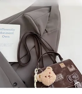 Detail of brown vintage crossbody bag with cute patches and plush bear charm on a suit