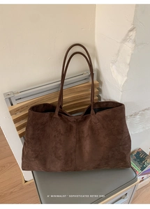 Detailopname van een grote bruine suède draagtas op een houten standaard in retrostijl
