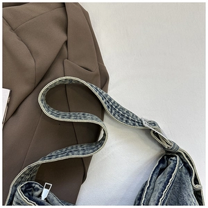 Detail van vintage denim hobo tas met gele stiksels en een zilveren metalen gesp