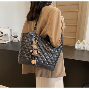 Detail of quilted black tote bag featuring a cute rabbit charm and fashion logo