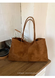 Detailopname van de vintage bruine suède tas met slanke lederen handgrepen