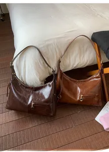 Detail of dark and red brown tote bags with crinkle patent leather texture on a white bed