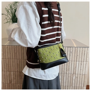 Détail du sac seau matelassé vert avec strass et bandoulière en cuir sur modèle