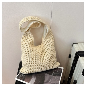 Detailed close-up of handmade hollow woven hobo bag with inner lining on a magazine