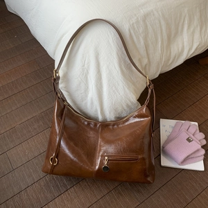 Detailed texture of brown wax leather hobo bag with gold hardware and zipper pocket