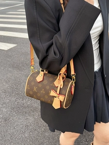 Brown monogram boston bag with leather handles and gold hardware in an urban street setting