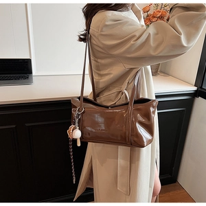 Detailed shot of brown glossy leather shoulder bag with creative baseball charm accessory