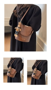 Detailed view of a dark brown bucket bag with braided handle and cute bunny pendant