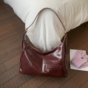 Detailed macro view of the burgundy wrinkled leather finish and gold zipper on hobo bag