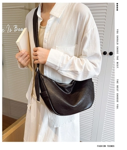 Detailed view of a black crescent hobo bag with embossed logo and metal zipper