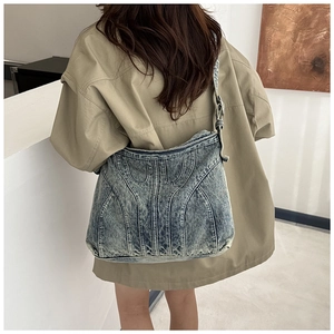 Detail van vintage denim crossbody tas met gewassen blauwe stof en stikselwerk