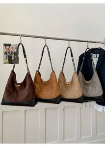 Detail of four colorful suede hobo bags with golden twist locks and chain straps