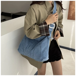 Detail van lichtblauwe denim hobo tas met verstelbare riem en metalen oogjes