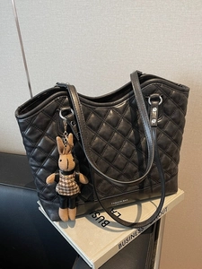 Chic black quilted tote bag with a small rabbit charm on minimalist background