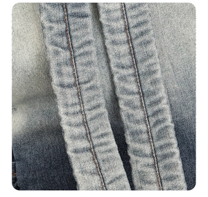Detailed close-up of double-stitched seams on gradient blue denim backpack fabric