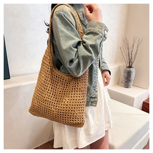 Detailed close-up showing the hollow out texture of a large woven straw shoulder bag