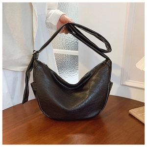 Detailed close-up of textured black crescent bag with wide adjustable shoulder strap