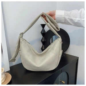 Detail view of cream white crescent hobo bag with silver zipper and wide shoulder strap