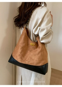 Detail of retro suede bucket bag featuring chain strap and gold twist-lock closure