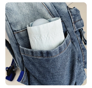 Close-up of compact blue folding umbrella stored in denim backpack side pocket for portability